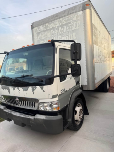 Truck cab and box side view showing International CF500 front with damaged bumper and box body