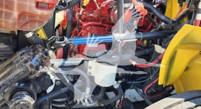 Engine bay of a 2021 International MV truck with red engine components and yellow body parts, showing hoses, belts, and wiring harnesses.