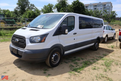Ford Transit 350 van in a dirt lot, front and side view, white cargo van with black bumper and windows.