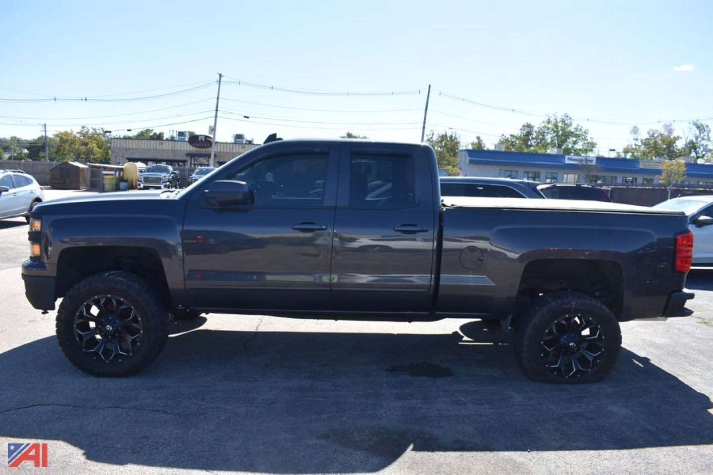 Truck side profile showing a 2015 Chevrolet Silverado 1500 with large black wheels and 4x4 extended cab.