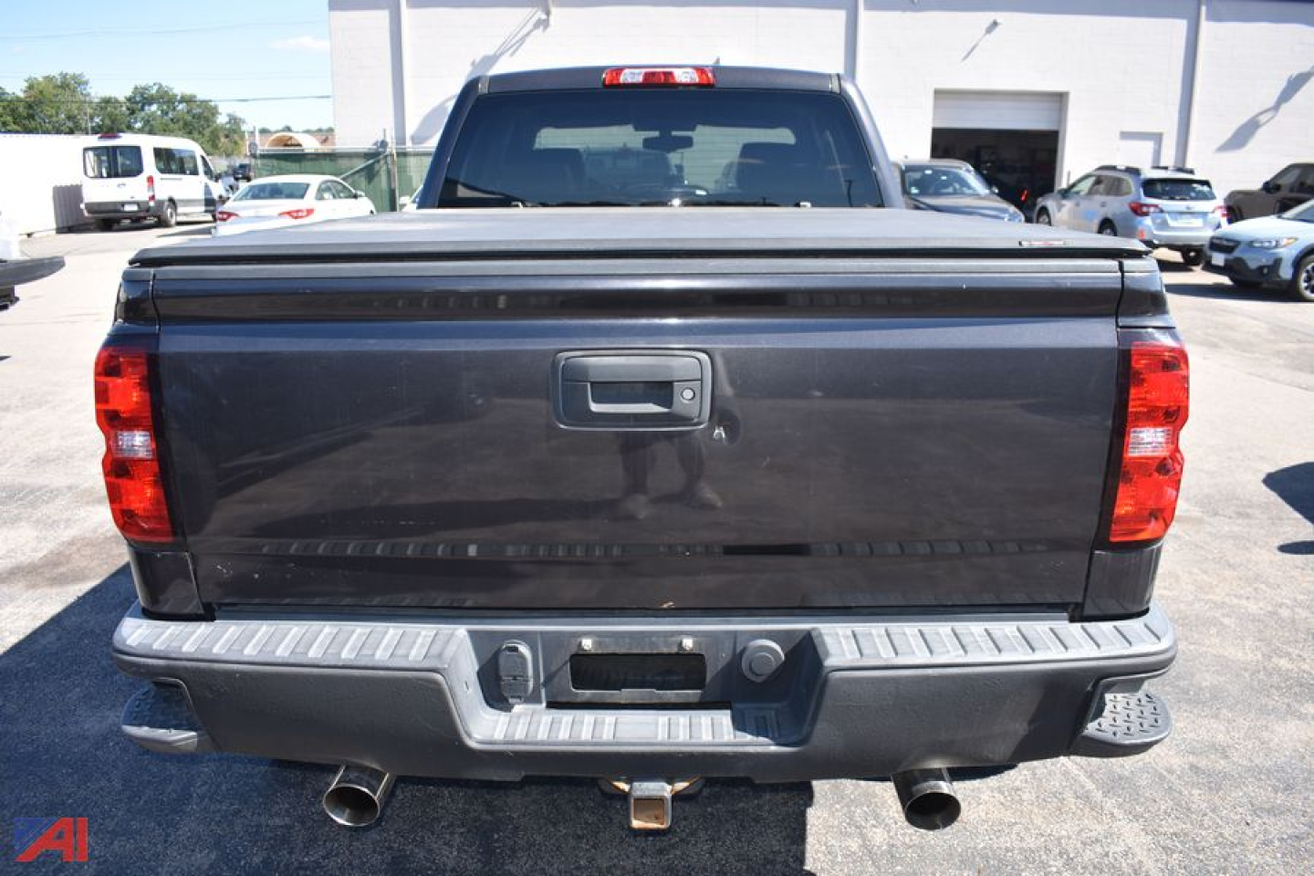 Chevrolet Silverado 1500 rear view showing tailgate, bumper, exhaust, and hitch with reflective surface.