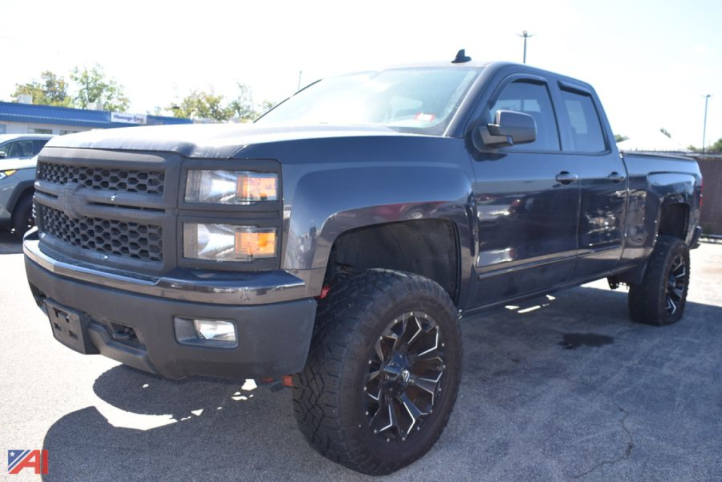 Chevrolet Silverado 1500 pickup in dark blue with lifted suspension and large off-road tires, front three-quarter view.