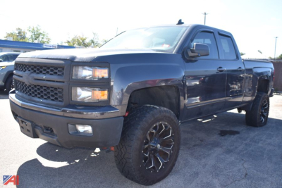 Chevrolet Silverado 1500 pickup in dark blue with lifted suspension and large off-road tires, front three-quarter view.