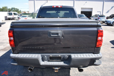 Chevrolet Silverado 1500 rear view showing tailgate, bumper, exhaust, and hitch with reflective surface.