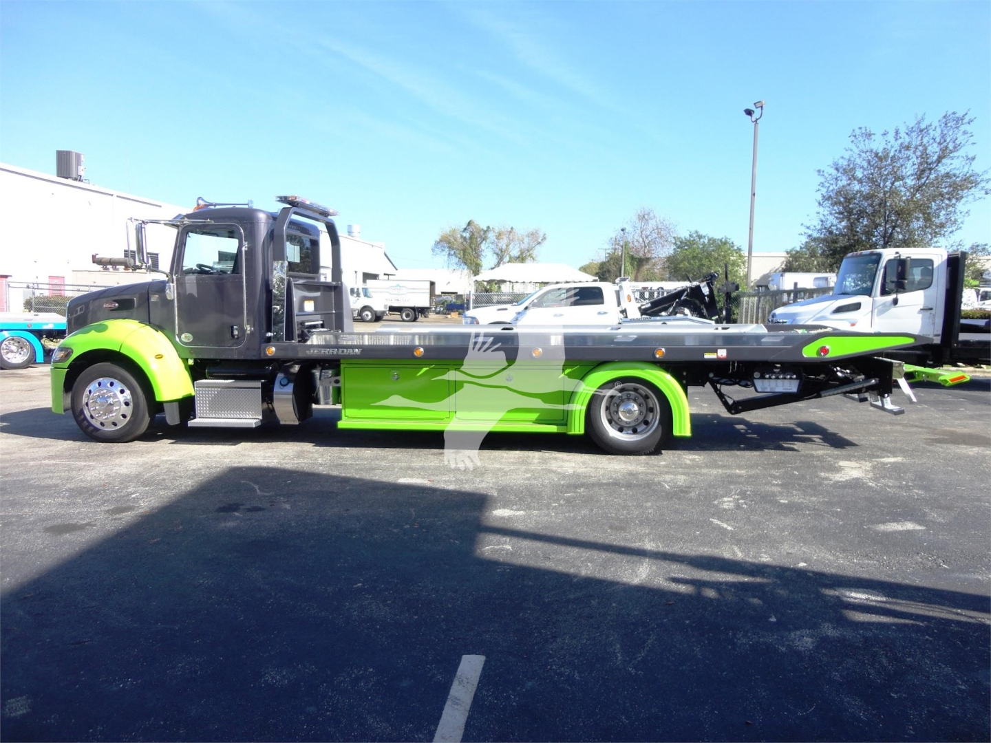 2022 Peterbilt 337 rollback truck side view showing bright green and black color scheme, long flatbed with towing equipment, cab with dual doors.