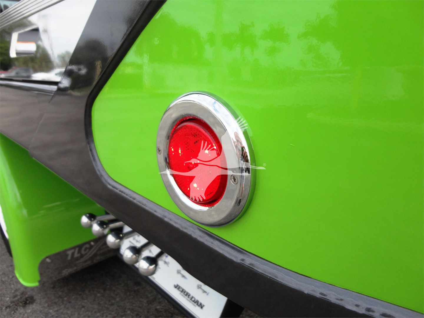 Rear quarter of a bright green 2022 Peterbilt 337 rollback truck showing a red circular tail light and chrome ring.