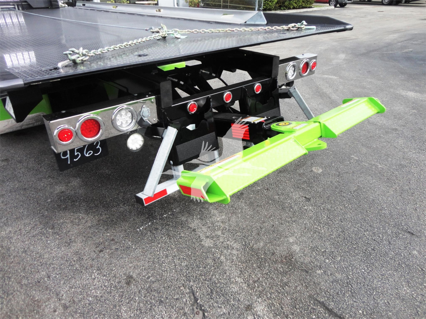Rear view of a new 2022 Peterbilt 337 rollback tow truck showing a bright green tow arm assembly and platform with rear lights and chains.