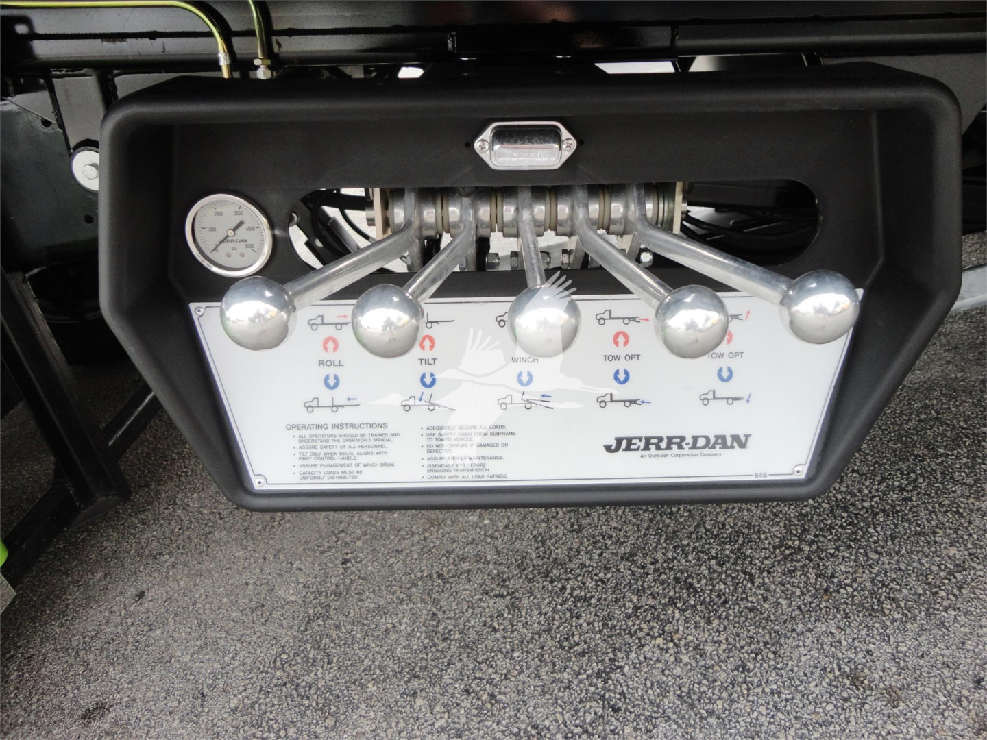 Jerr-Dan control panel showing levers and gauges with labels for Roll, Tilt, and Tow in button layout on a rollback truck.