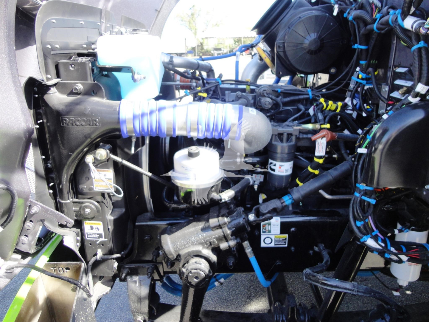 Peterbilt 337 engine bay view showing turbocharger, hoses, wiring, and hydraulic/air components; multiple colored clamps and labels visible.