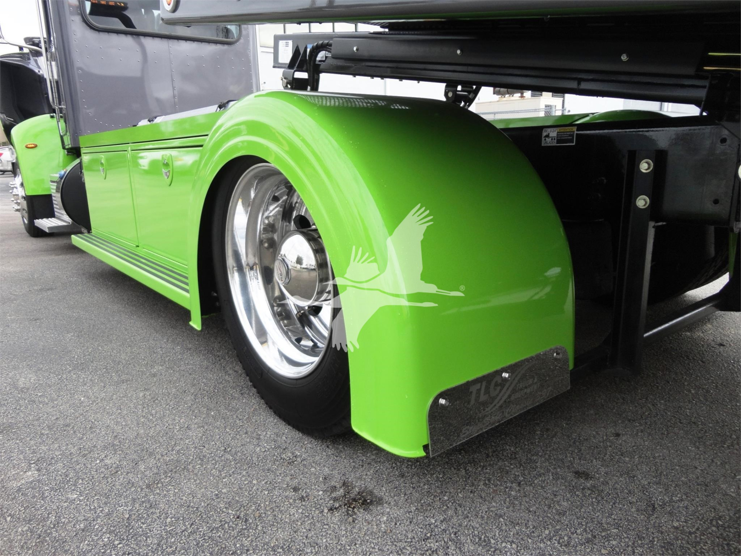 Truck fender and wheel area of a 2022 Peterbilt 337 rollback truck with lime green fender and chrome wheel.
