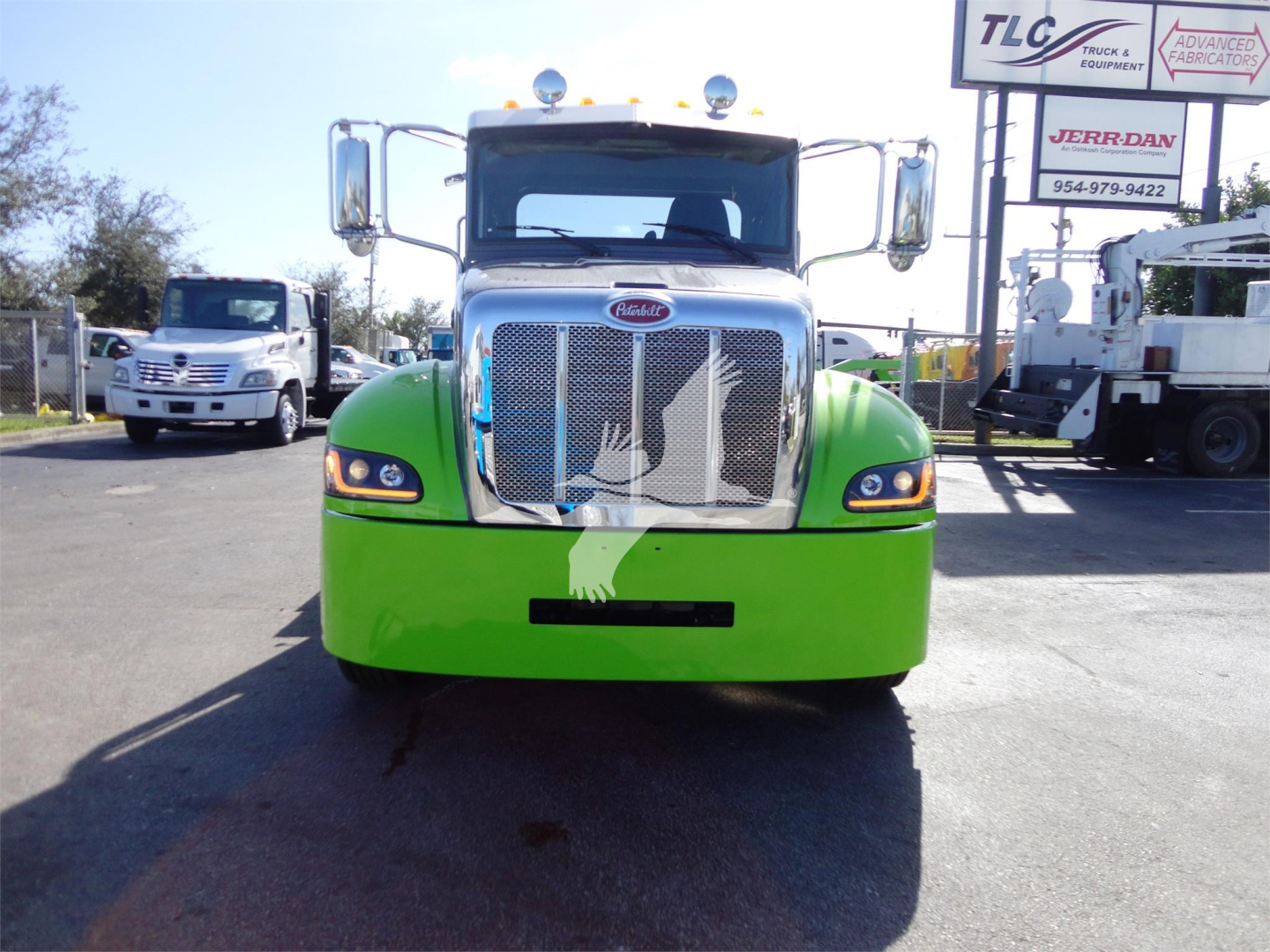 Peterbilt 337 truck facing camera in bright green color with chrome grille and headlights, front view.