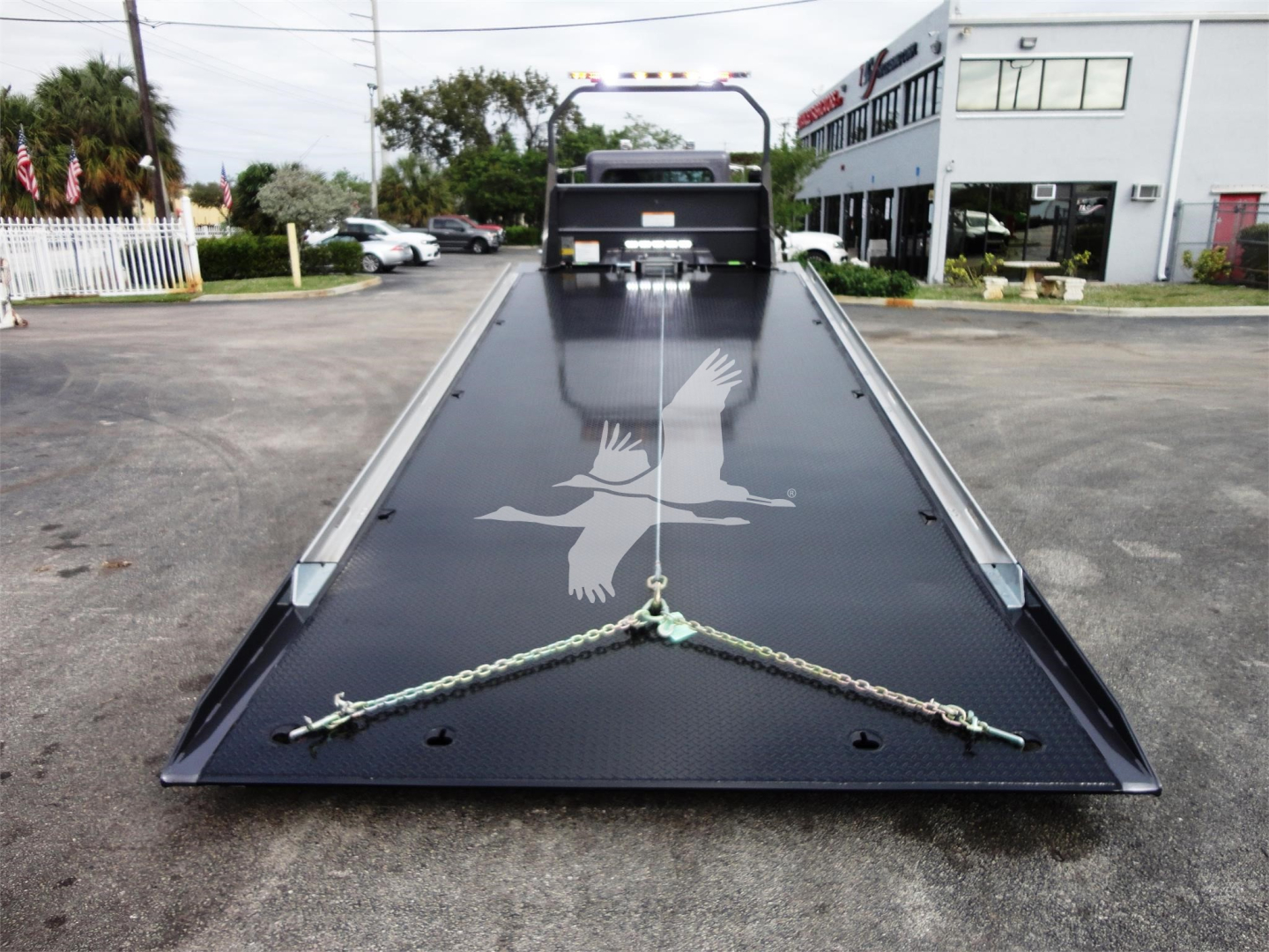 Peterbilt 337 rollback flatbed with ramp at front, chain winches, and decorative eagle graphic on the bed.