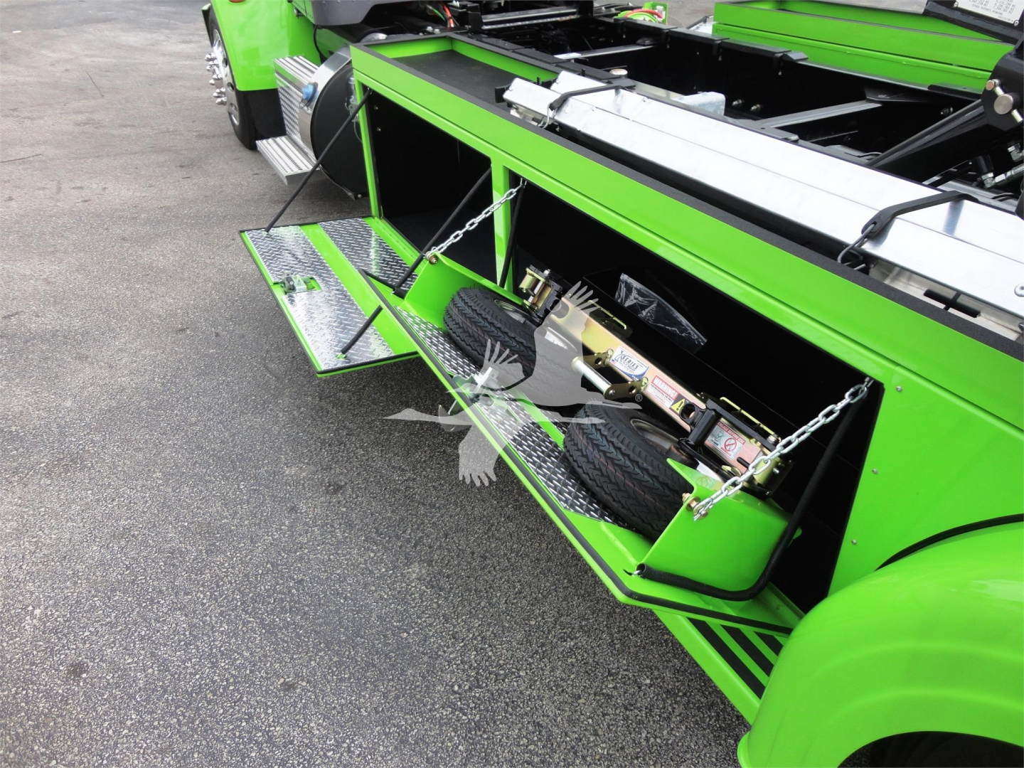 Peterbilt 337 rollback truck with bright green body and open side tool compartments showing steps and auxiliary equipment.