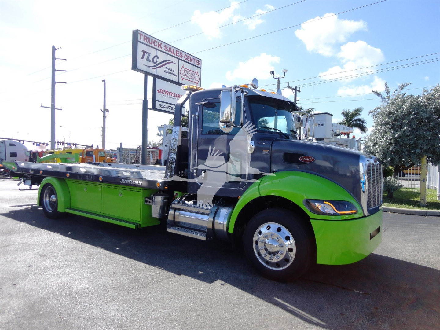 Peterbilt 337 rollback tow truck profile with black cab and bright green lower body, stock number J56626 visible at dealership lot.