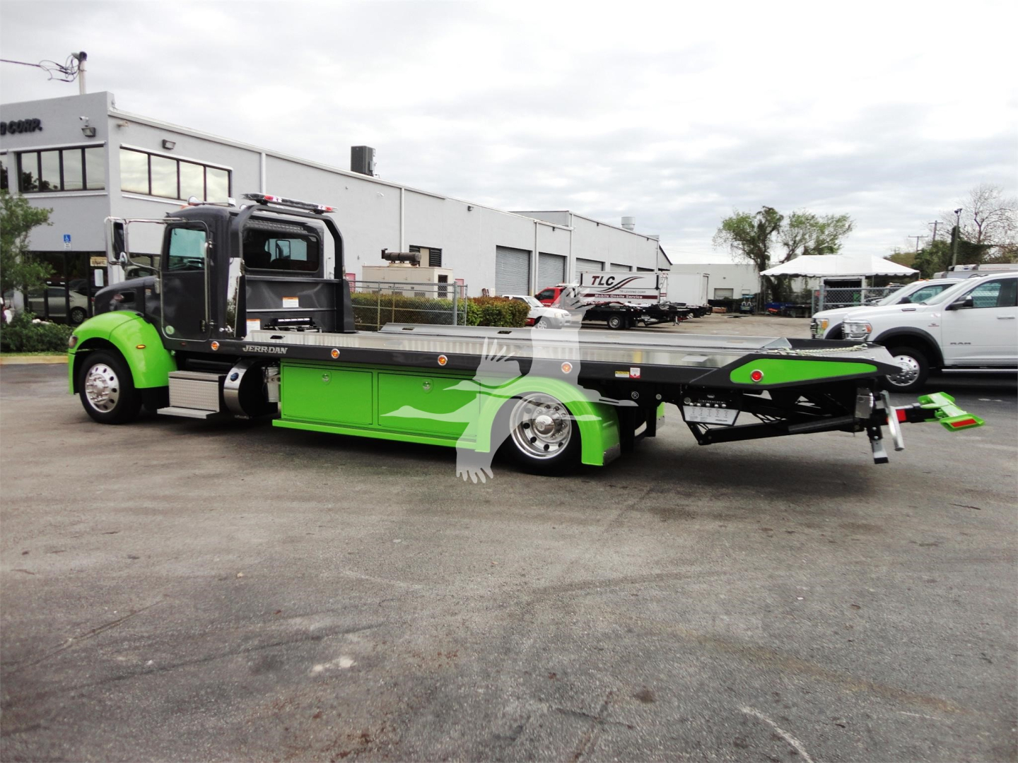 Peterbilt 337 rollback tow truck in bright green and black livery, side view showing low-profile flatbed with hydraulic lines and wheel platforms.
