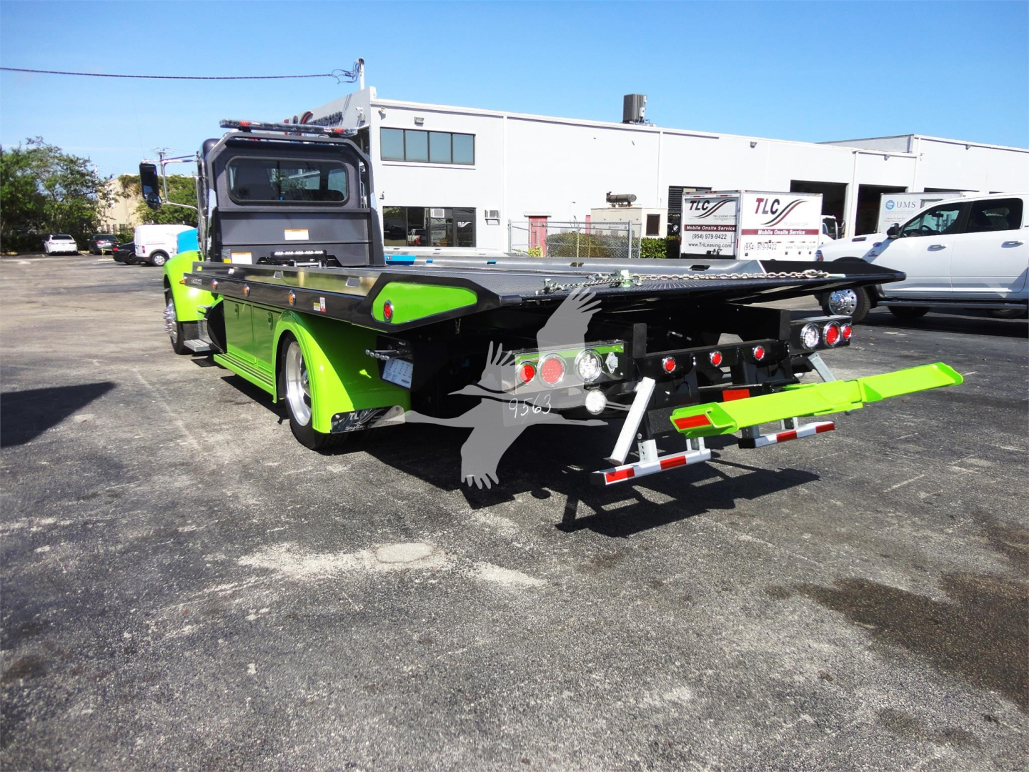 Peterbilt 337 rollback tow truck rear view showcasing bright green equipment with flatbed and rear ramps.