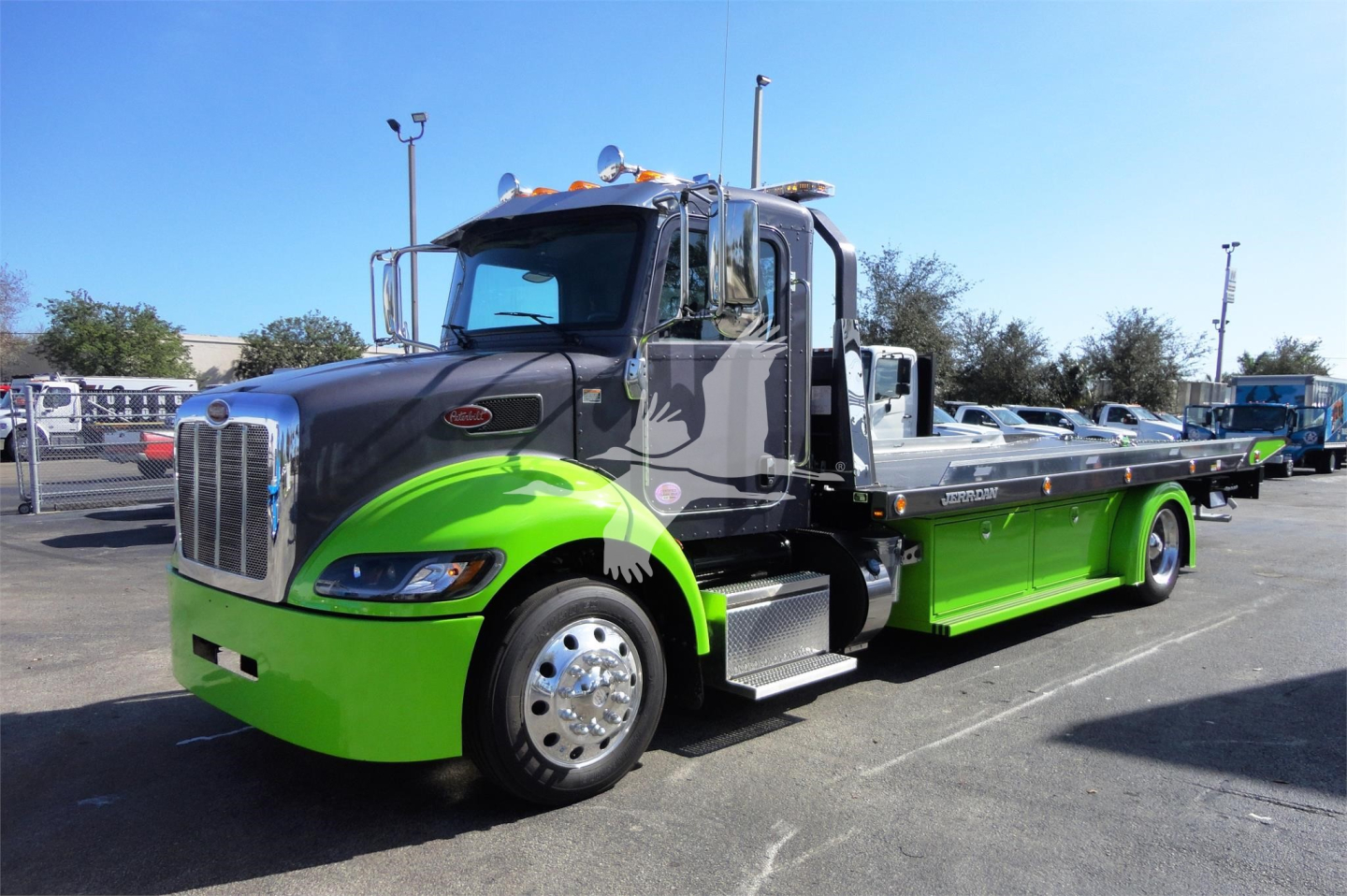 Peterbilt 337 rollback truck showing bright green lower body and black cab with chrome mirrors and Sleeper cab, front view angled.