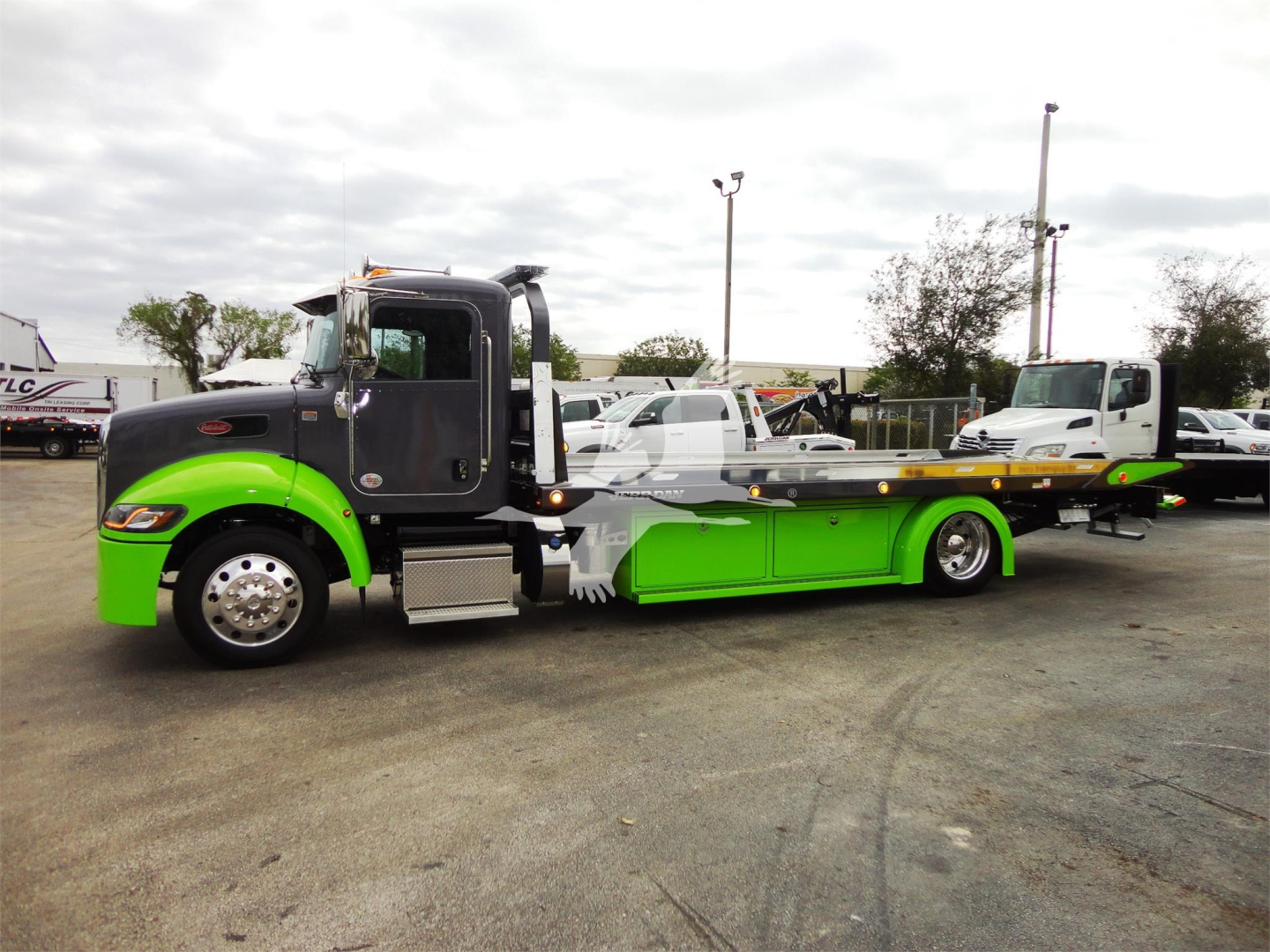 Truck image: 2022 Peterbilt 337 rollback with lime green accent on bumper and lowbed, side view showing cab and tow deck