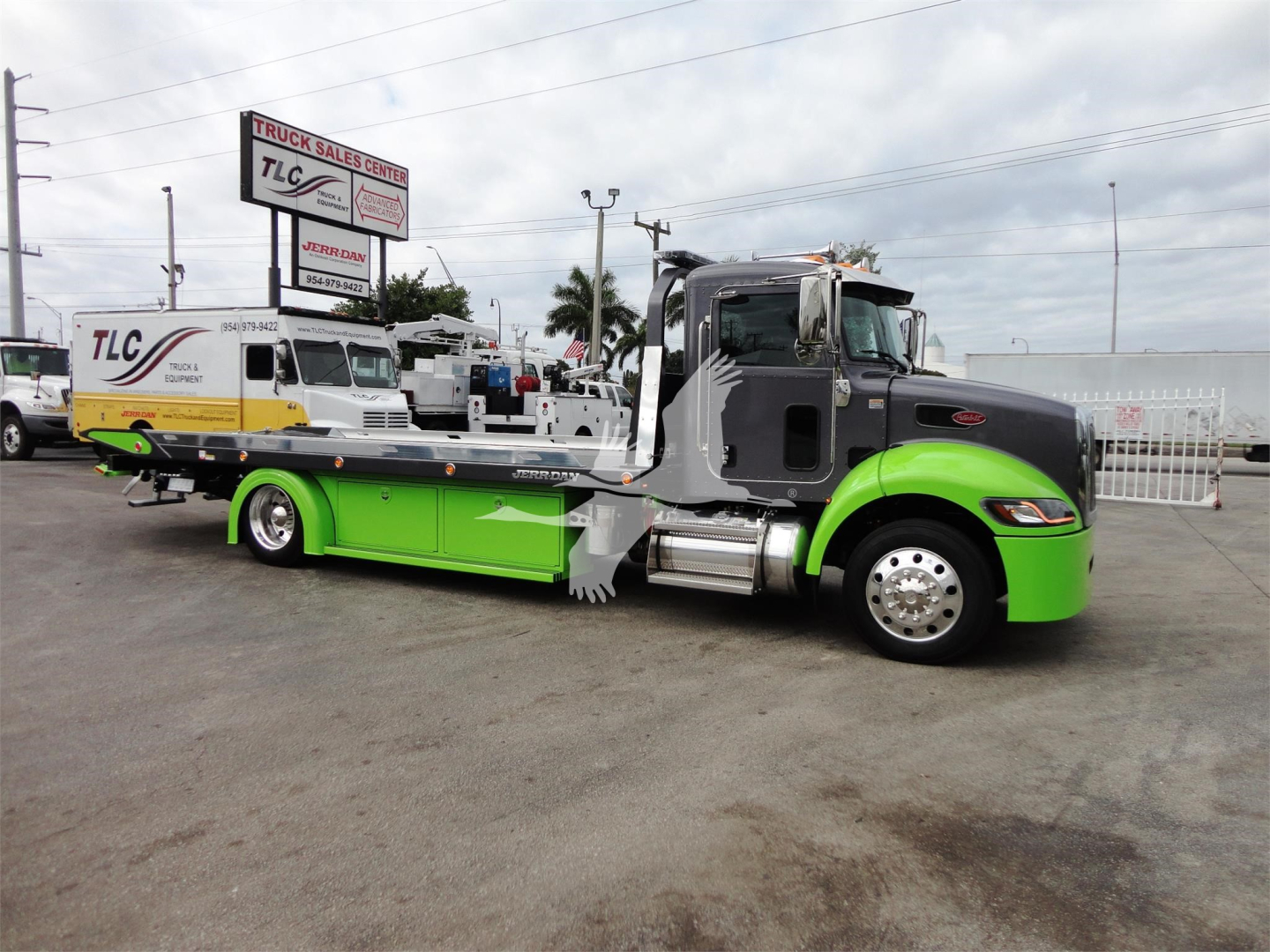 Peterbilt 337 rollback tow truck in green and black livery with a green undercarriage, side mirror, and chrome wheels.