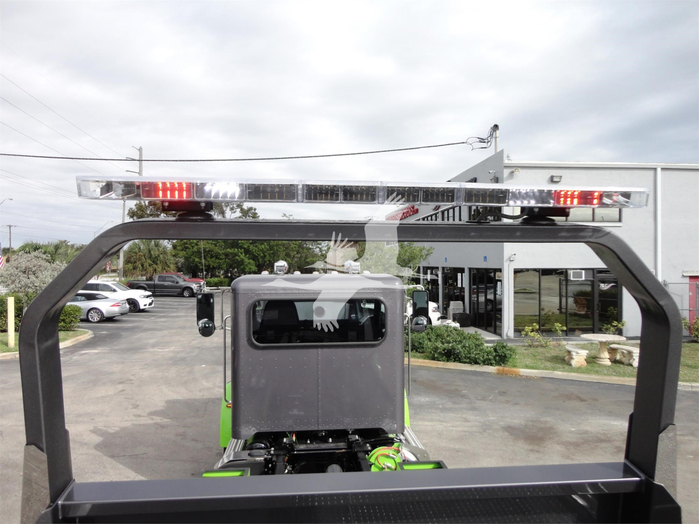 Peterbilt 337 rollback truck with rear view showing ladder rack and cab, dealership lot in background.