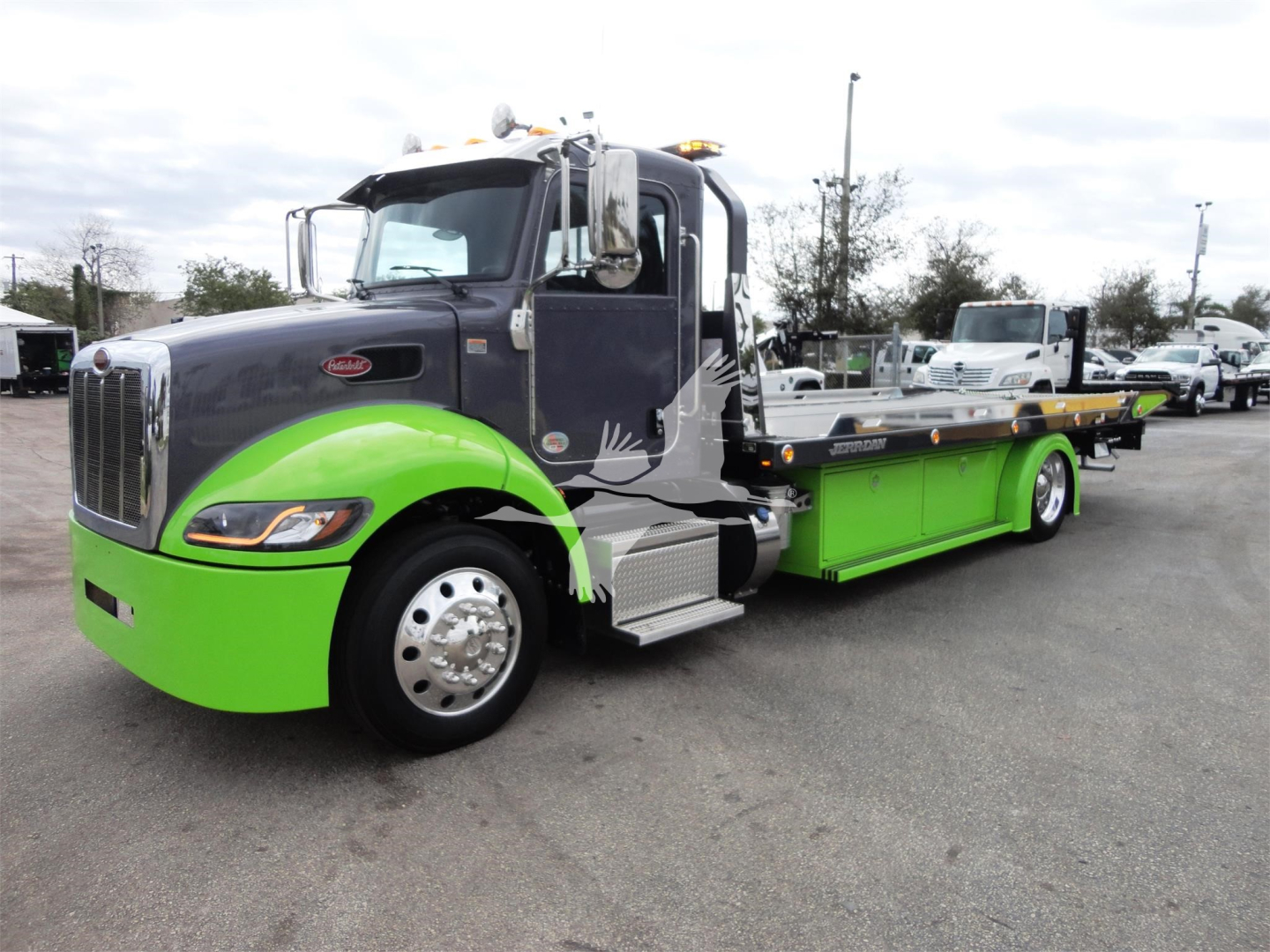 Peterbilt 337 rollback truck with bright green accents and gray cab, side view showing flatbed and wheels.