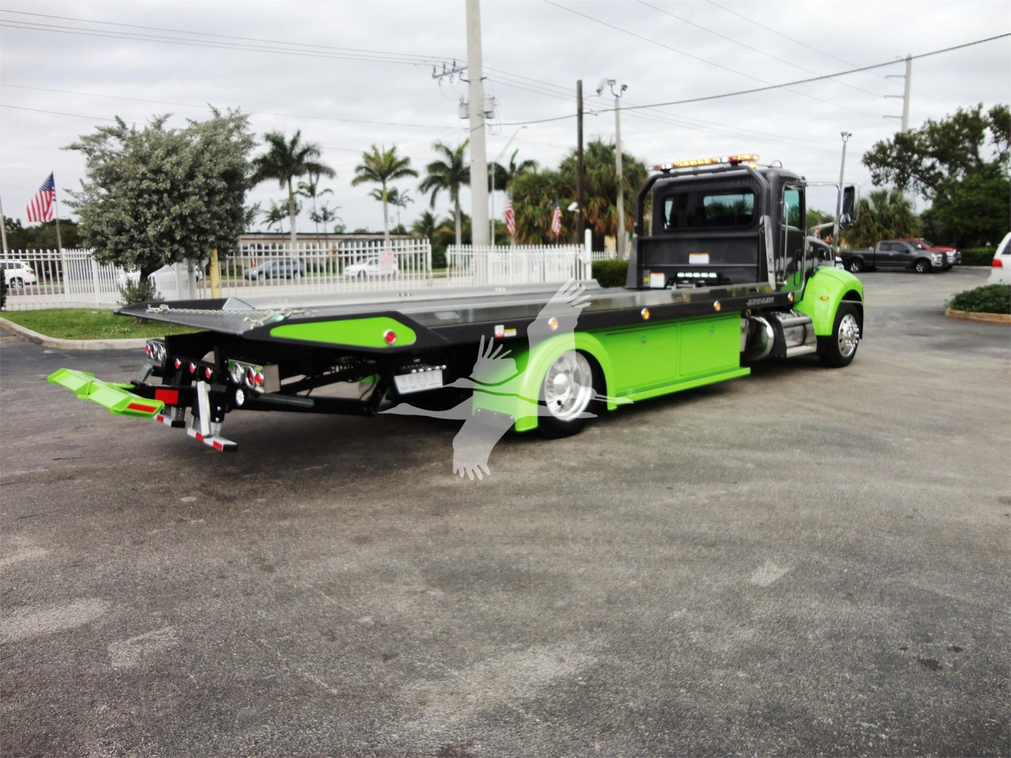 Peterbilt 337 rollback tow truck with bright green and black color scheme, flatbed extended, rear view showing equipment.