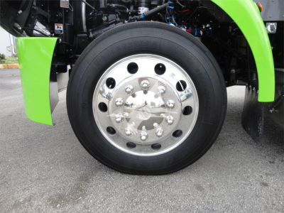 Truck wheel close-up showing chrome hub, green fender, and tire tread on Peterbilt 337 rollback truck.