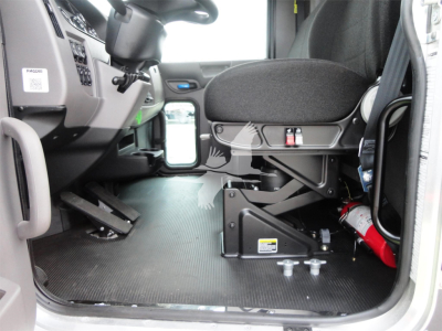 Peterbilt 337 cab interior showing driver seat, dashboard, and floor area with a mounted device and fire extinguisher.