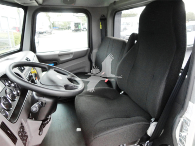 Truck cab interior showing steering wheel, dashboard, and two black seats in a Peterbilt 337 rollback trucks listing.