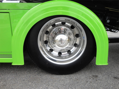 Green Peterbilt 337 wheel and chrome wheel well with polished steel rim and lug nuts visible.