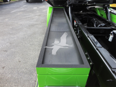 Green Peterbilt 337 rollback truck with a long narrow black mesh air intake featuring a white bird graphic.