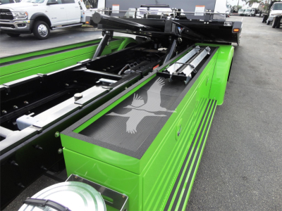 Green Peterbilt 337 rollback bed with hydraulic components and storage toolbox visible, top view of truck bed and hydraulic arms.