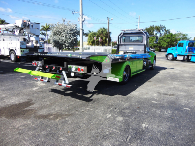 Peterbilt 337 rollback truck in bright green with flatbed, rear loading ramps extended, side mirrors, and chrome wheels.