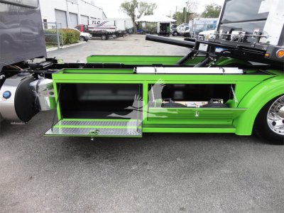 Peterbilt 337 side view showing open tool/storage compartments on green truck with chrome accents