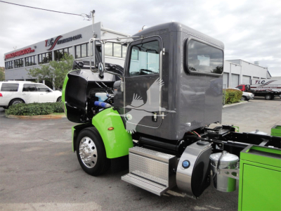 Peterbilt 337 truck in a rollback configuration showing green chassis and gray cab with steps and fuel tanks visible.
