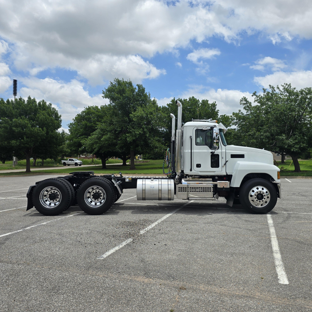 Truck side profile: 2027 Mack PI64T conventional daycab tractor, white cab, chrome exhaust stacks, fuel tanks, and dual rear axles.
