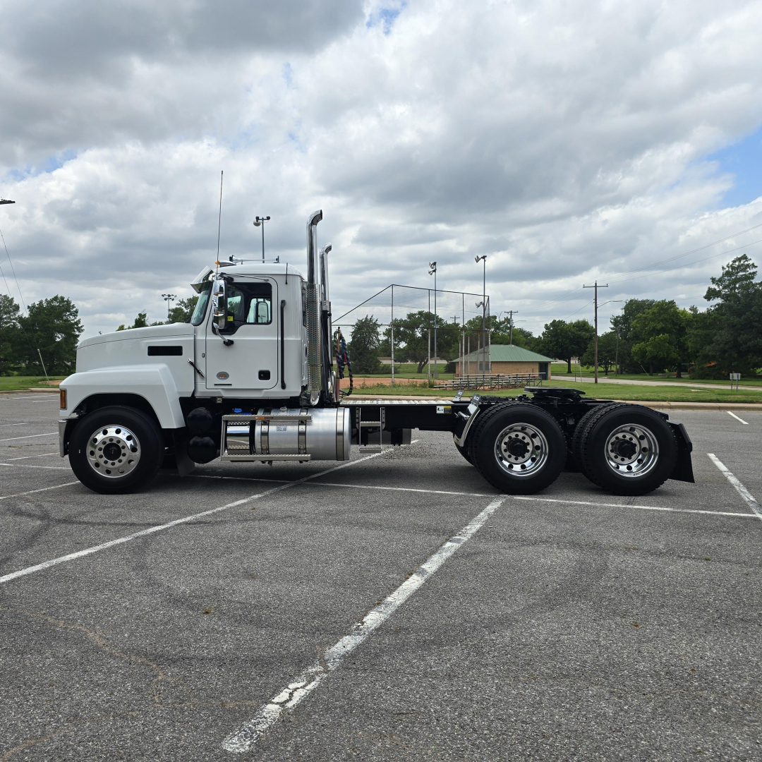 Truck chassis and cab side view of a 2027 Mack PI64T conventional daycab showing chrome fuel tanks, exhaust stack, and dual rear axles.
