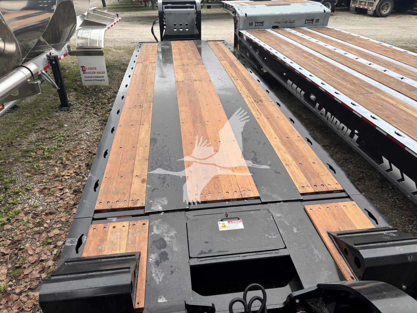Trailer deck of a Fontaine 55MX lowboy showing wooden deck sections with metal frame and grip mats; VIN tag and stock number not visible; reflective watermarks in image.