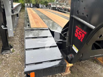 Lowboy trailer rear view showing wooden deck and ramp with Fontaine 55MX branding on the side, black metal frame, and wheel area. Text visible includes 'FONTANNE 55MX' on the ramp hinge.