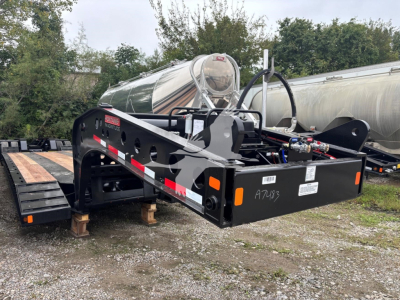 Fontaine lowboy trailer frame showing A75?3 markings, hydraulic lines, and toolkit on black steel with reflective tape; side rails and hitch area visible.