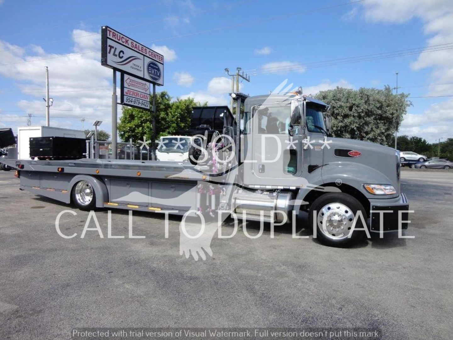 Peterbilt 337 rollback tow truck in side view showing long flatbed and dual rear wheels with the Peterbilt hood and cab, dealership watermark across image.