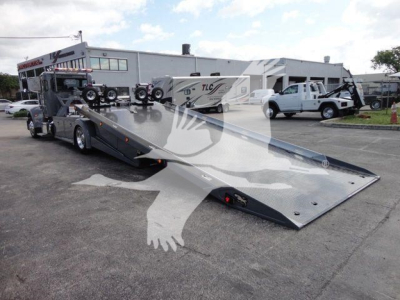 2022 Peterbilt 337 rollback truck with low-angle tilted flatbed in a dealership lot.