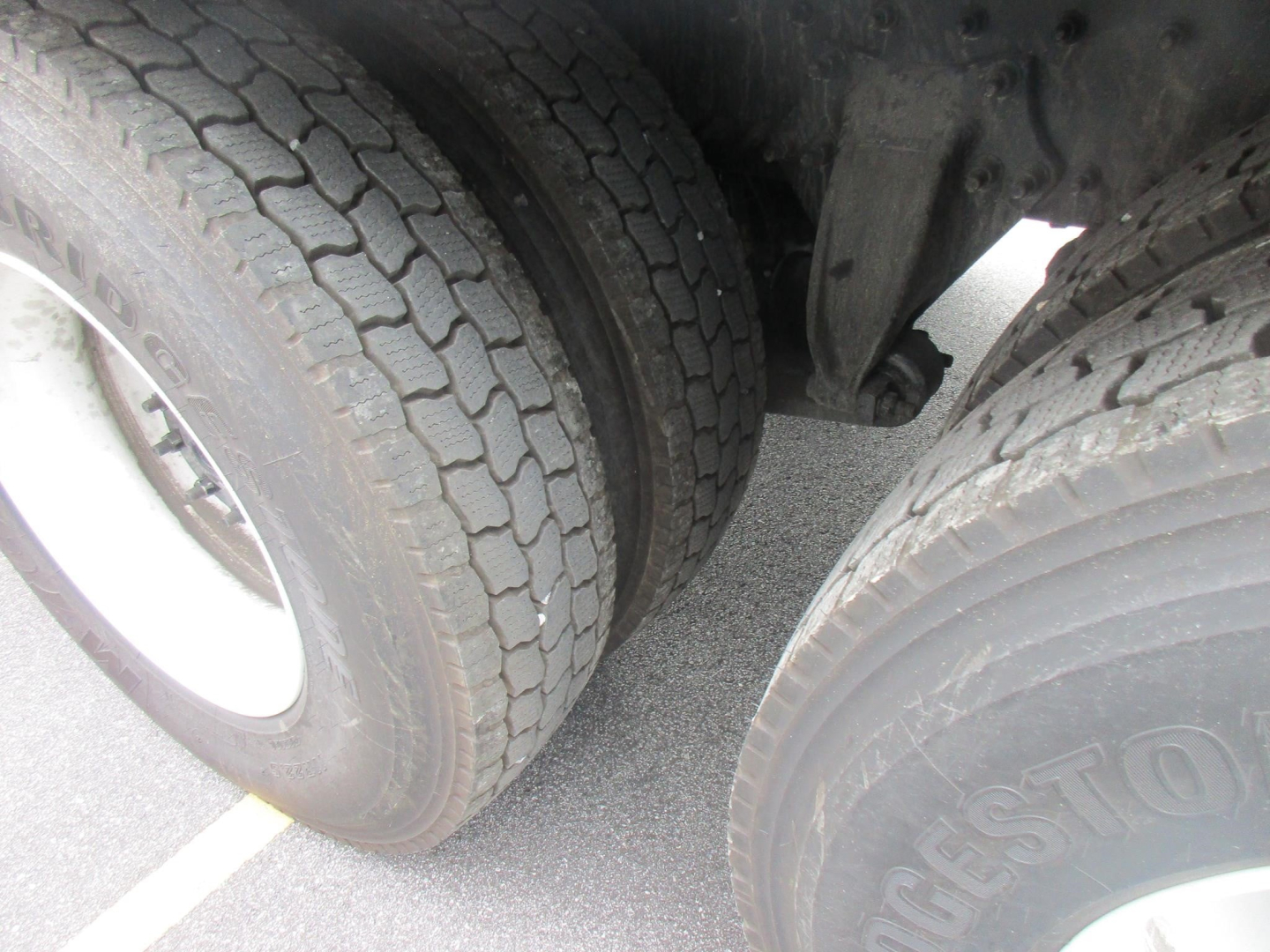 Freightliner M2 106 Plus wheel area showing dual rear tires and part of suspension; tread pattern visible on tires.