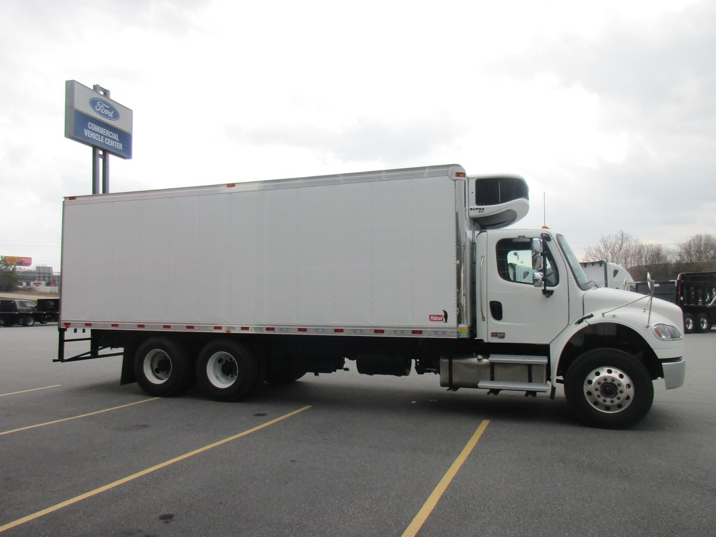 Freightliner M2 106 Plus refrigerated truck side view with cargo box and aerodynamic cap on cab.