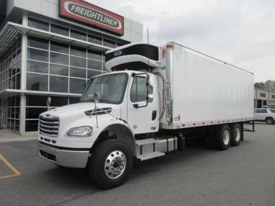 Freightliner Business Class M2 106 Plus refrigerated truck in front of dealership, cab with side mirrors and white box trailer.