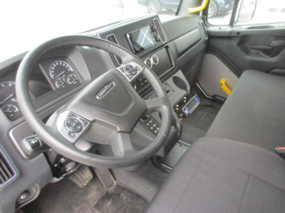 Truck cabin view of a 2026 Freightliner M2 106 Plus showing steering wheel and dashboard with controls and center console.