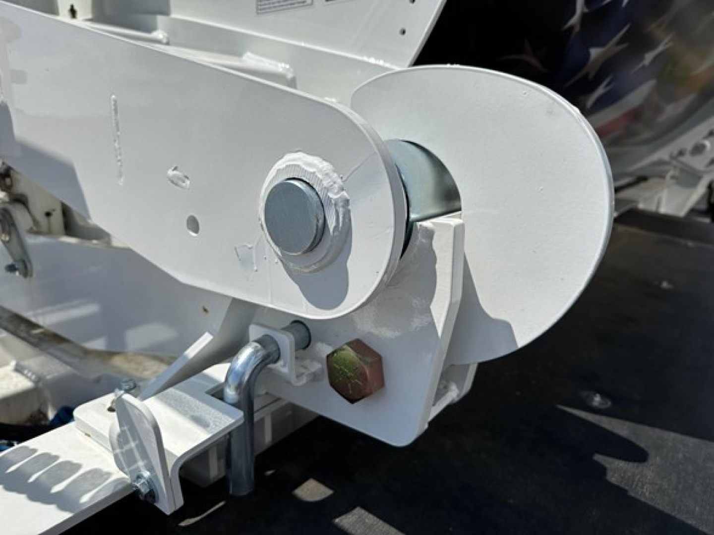 Trailer component showing a circular hitch/pulley assembly with bolts and a metal latch, part of a side-dump trailer.