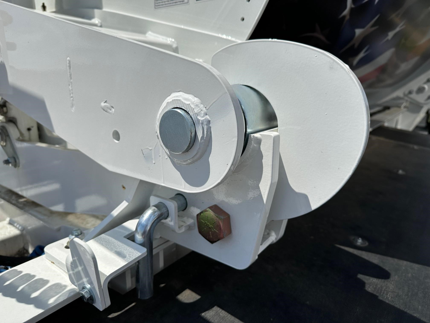 Trailer component showing a metallic wheel-like pivot and latch assembly on a wear-resistant grey surface, likely part of a side dump trailer mechanism.
