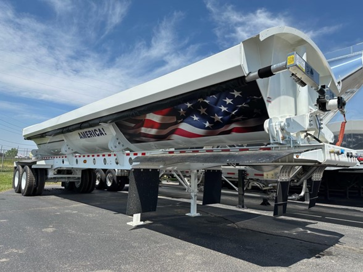 Jet Side Dump trailer showing federal-style american flag graphic on the side and mechanical hitch details.