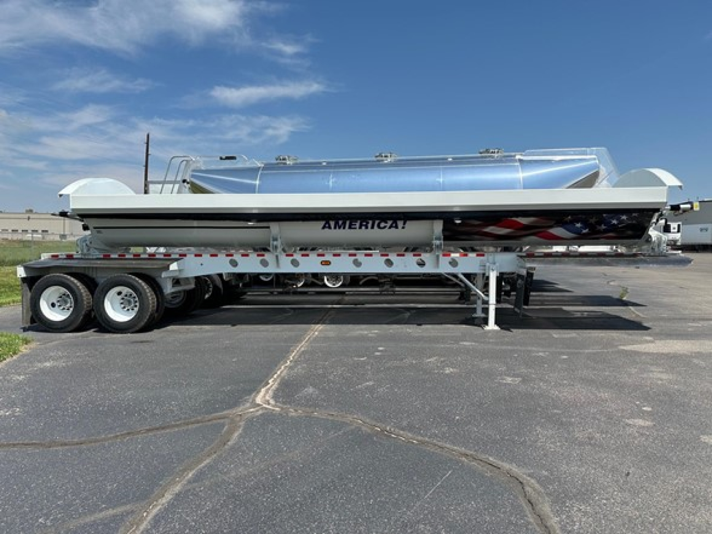 Trailer side-dump semi-trailer with aluminum dump body and dual rear axles. Cargo area label AMERICA! on white and gray surface; tandem wheels and landing gear visible.